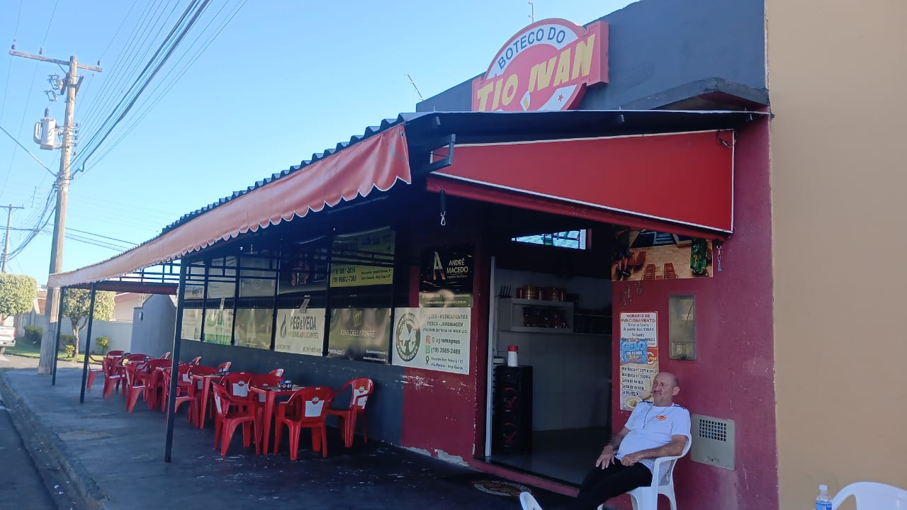 Fachada do Boteco do Tio Ivan com letreiro vermelho e mesas na calçada
